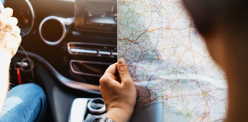 Hipster Man Holding In Male Hands And Looking On Navigation Map In Auto, Tourist Traveler Hiker Driving On Background View Way Road, Trip In Transportation, Person Sitting On Backdrop Window Auto